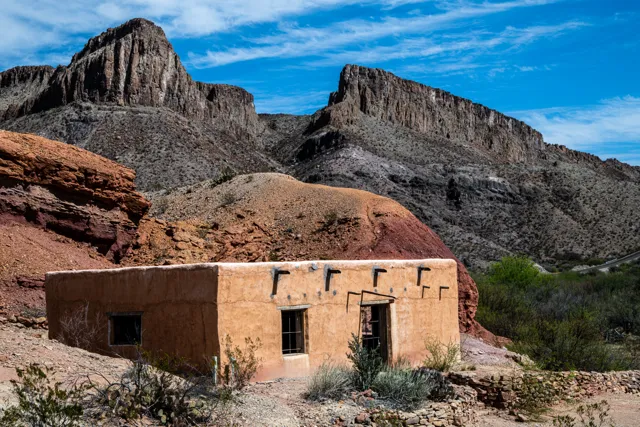 An adobe building at the Contrabando movie set sits beneath rugged rock formations and an open Texas sky.