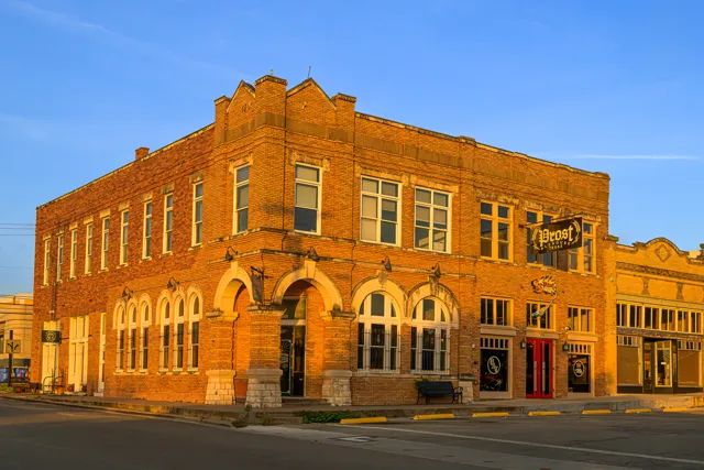 Warm light catches the brickwork and arched entrance of the historic building now home to Prost Alehouse.