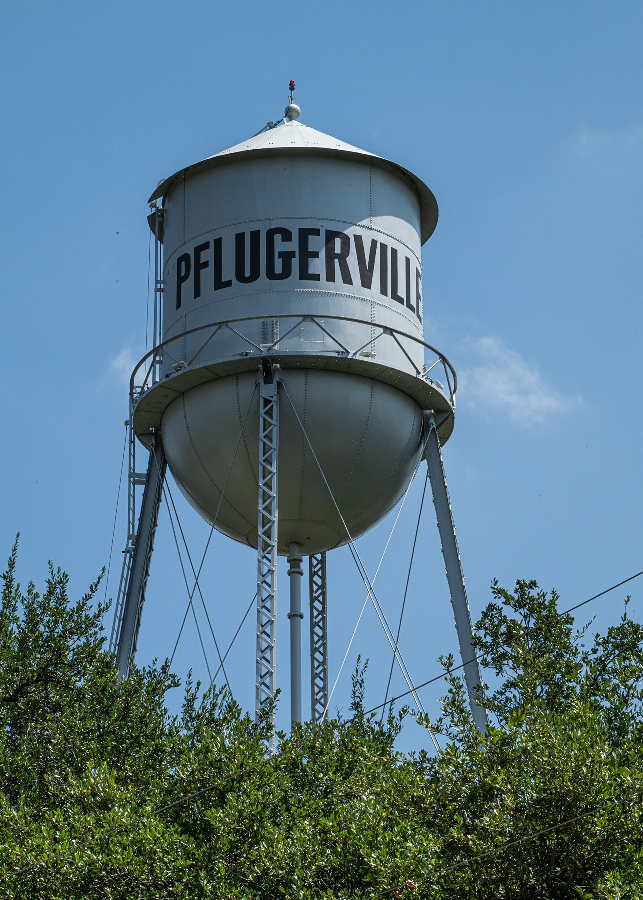Pflugerville water tower rising above trees in Pflugerville Texas